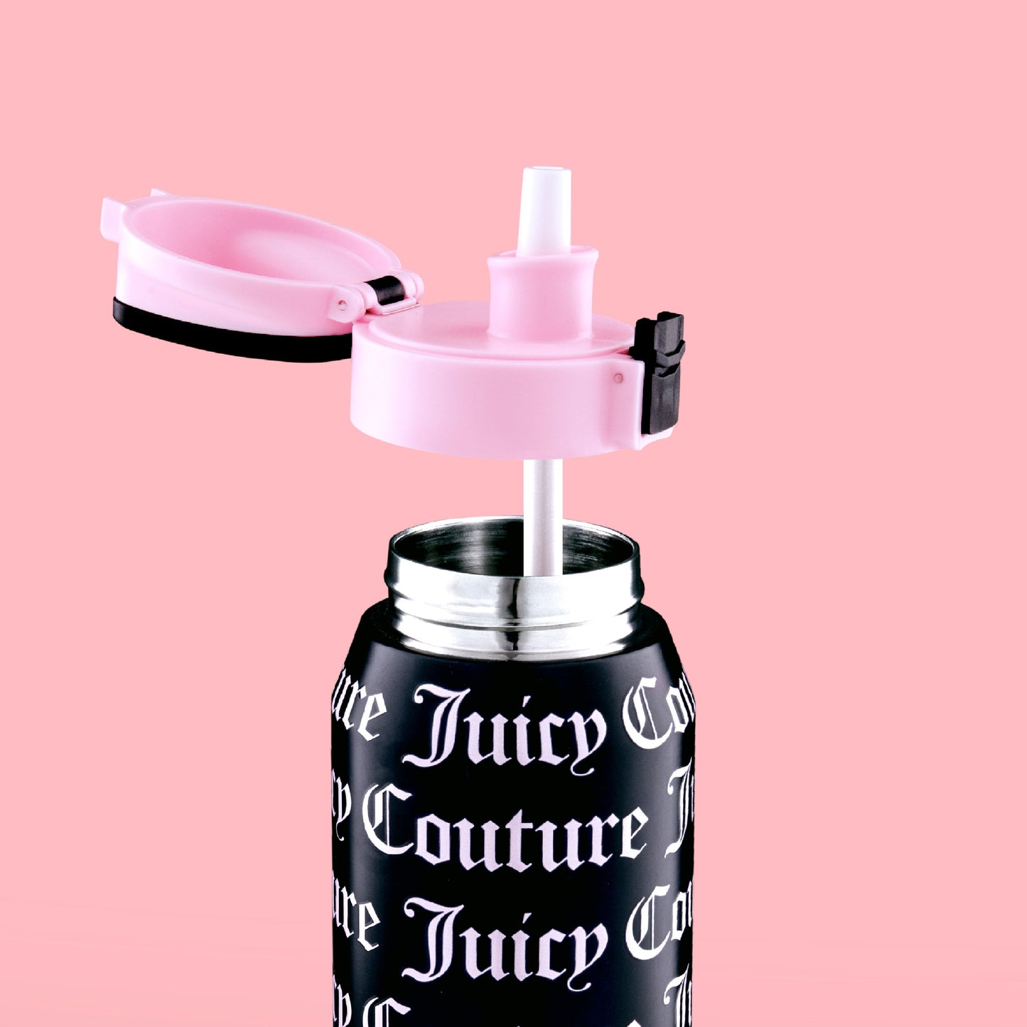 The Glam Getaway Hydration Stainless Steel Tumbler by Juicy Couture, featuring a black body, white gothic logo, pink flip-top lid, and white straw, is displayed against a solid pink background.