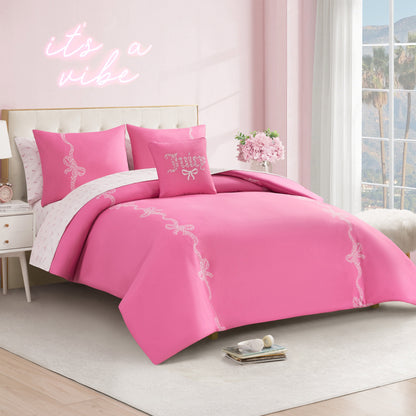 A neatly made bed with the Hotel Stripe Leopard Bows Bed in a Bag Bedding Set sits in a pastel pink room. Decorative pillows and a “it’s a vibe” neon sign are above, while sunlight streams in to reveal palm trees outside.
