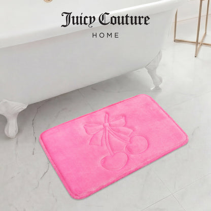 A bright pink Quilted Memory Foam Bath Mat, 17" x 24", with an embossed cherry and bow design sits on a white marble floor in front of a clawfoot tub, adding a stylish touch to your bathroom.