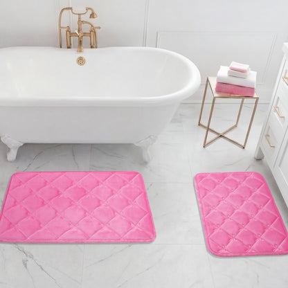 A white bathtub with gold fixtures stands next to a gold side table with folded towels. A Quilted Memory Foam Bath Mat 2-Piece Set in pink is placed on the white tile floor in this bright bathroom.
