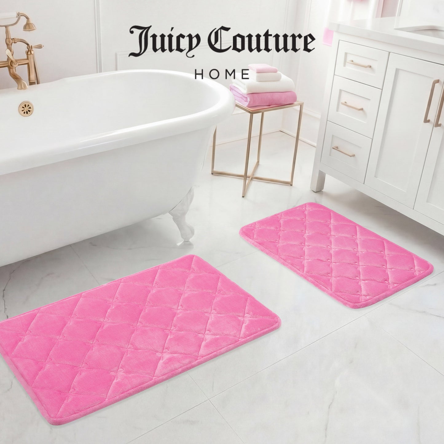 A white bathroom with a clawfoot tub, white vanity, and two Quilted Memory Foam Bath Mats on the floor. Folded pink and white towels sit on the vanity. Text: Juicy Couture Home.