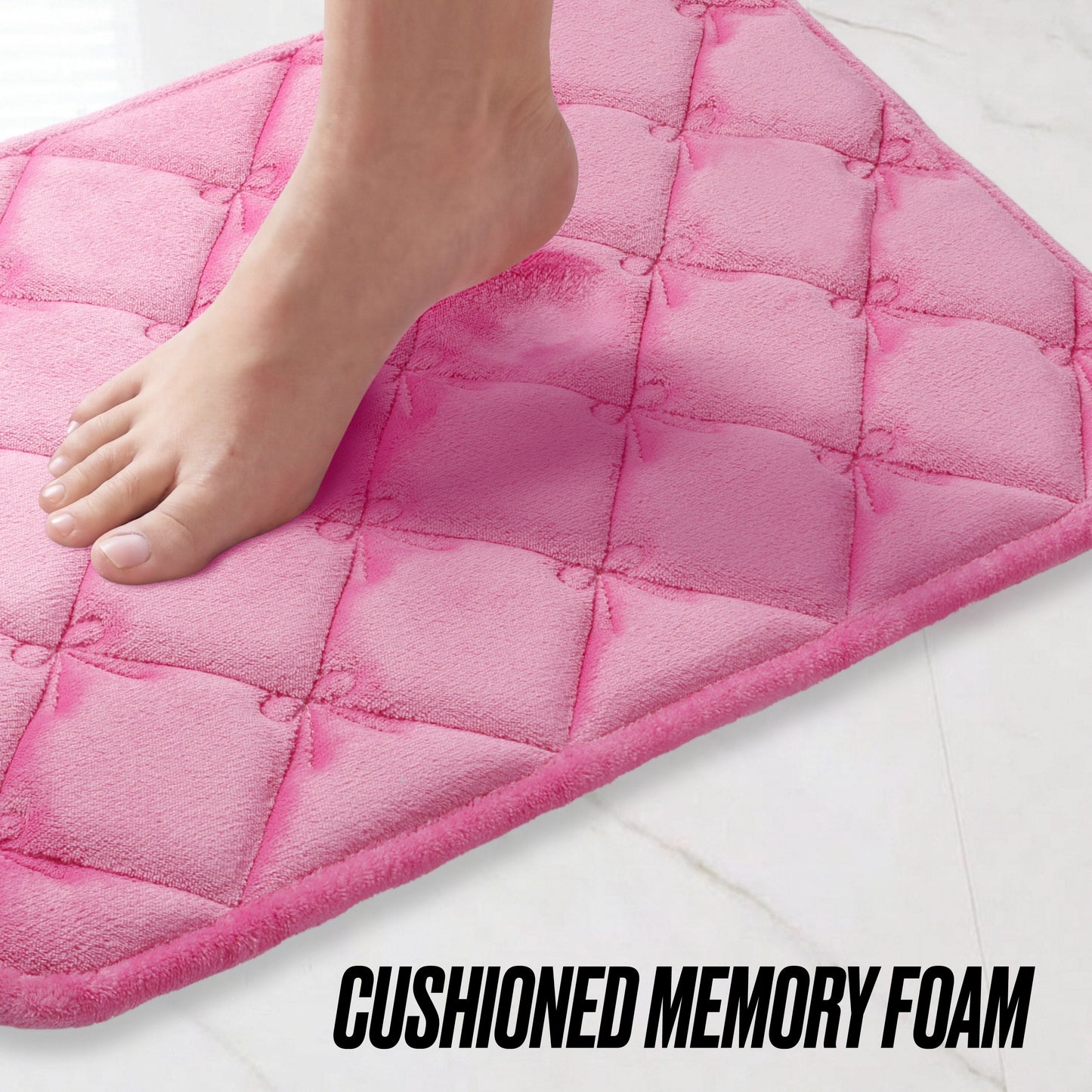 A bare foot steps onto a pink Quilted Memory Foam Bath Mat 2-Piece Set on a white tiled floor. The text at the bottom reads CUSHIONED MEMORY FOAM.