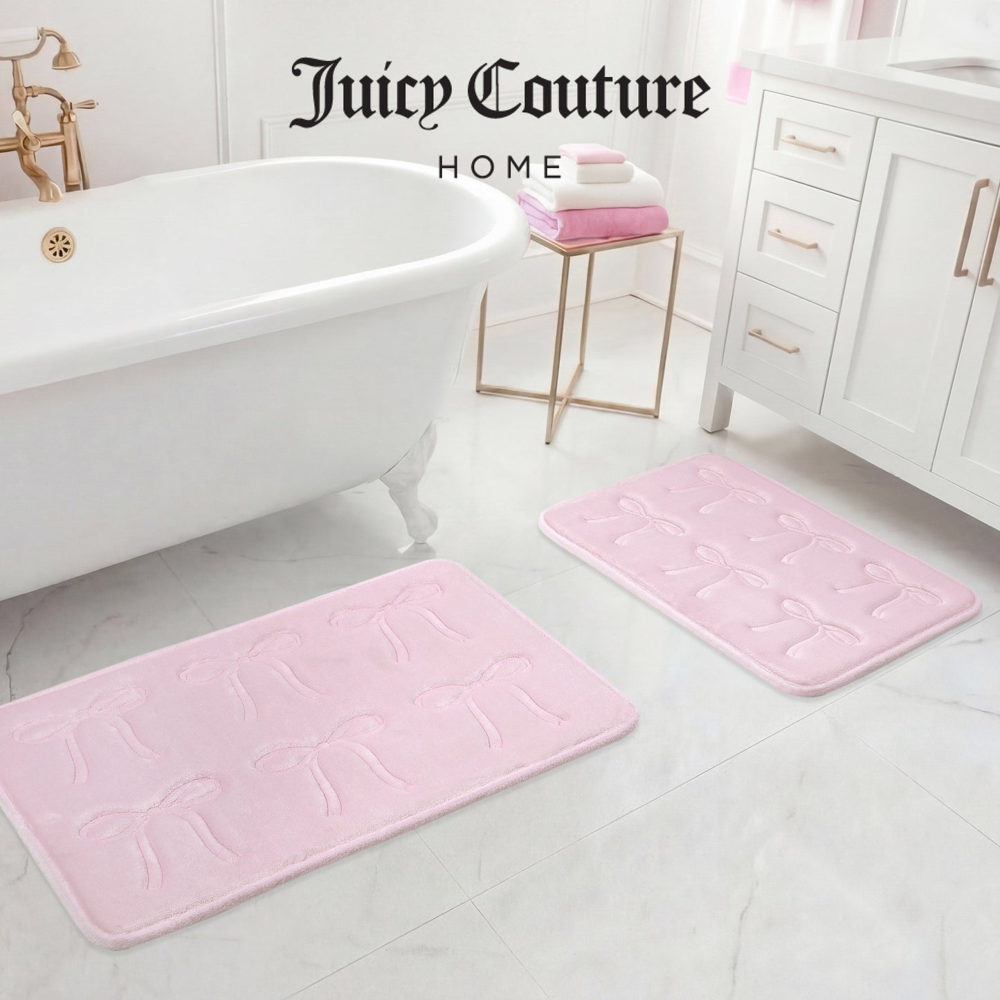 A white bathroom features a clawfoot tub, white vanity, and two light pink Juicy Couture Quilted Memory Foam Bath Mats. Folded pink and white towels rest on the vanity. “Juicy Couture Home” is written at the top.