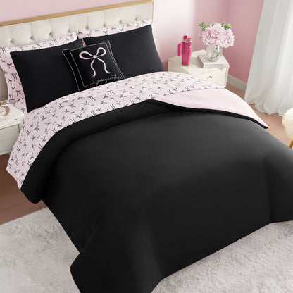 A neatly made bed with the Bows Solid Reversible Bed in a Bag Bedding Set in black and pale pink, featuring bow-patterned sheets and a decorative pillow. The room has pink walls, white nightstands, and flowers in a vase.