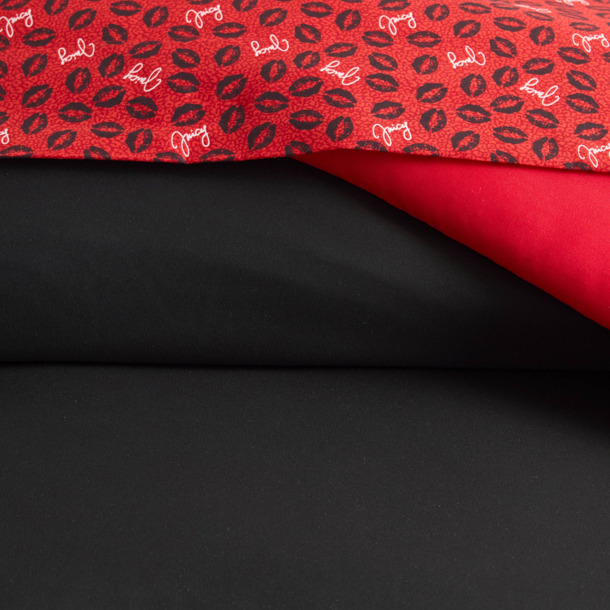 The Cheetah Rebel Lips Solid Reversible Bed in a Bag Bedding Set features an animal-inspired print with black lips and words, plus solid red and black fabrics—ideal for creating stylish, reversible bedding.
