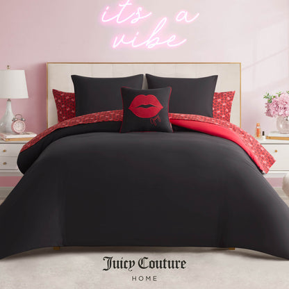 A stylish bedroom features the Cheetah Rebel Lips Solid Reversible Bed in a Bag Bedding Set with black and red animal print, a decorative red lips pillow, and a neon pink “it’s a vibe” sign above. Juicy Couture Home is printed at the bottom.