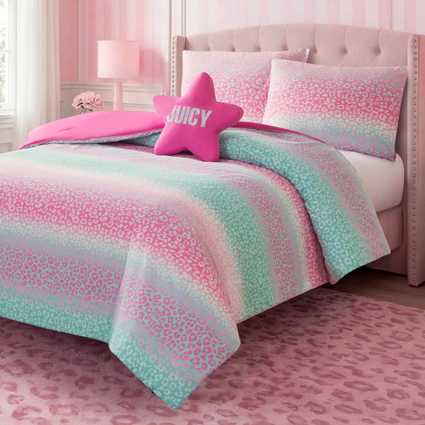 A stylish kids bedroom set features the Kids Rainbow Ombre Leopard Reversible Comforter Set from Juicy Couture, with its pink and mint green leopard print comforter, accented by a star-shaped JUICY pillow and a soft pink rug, all set against vibrant pink walls and coordinating furniture.