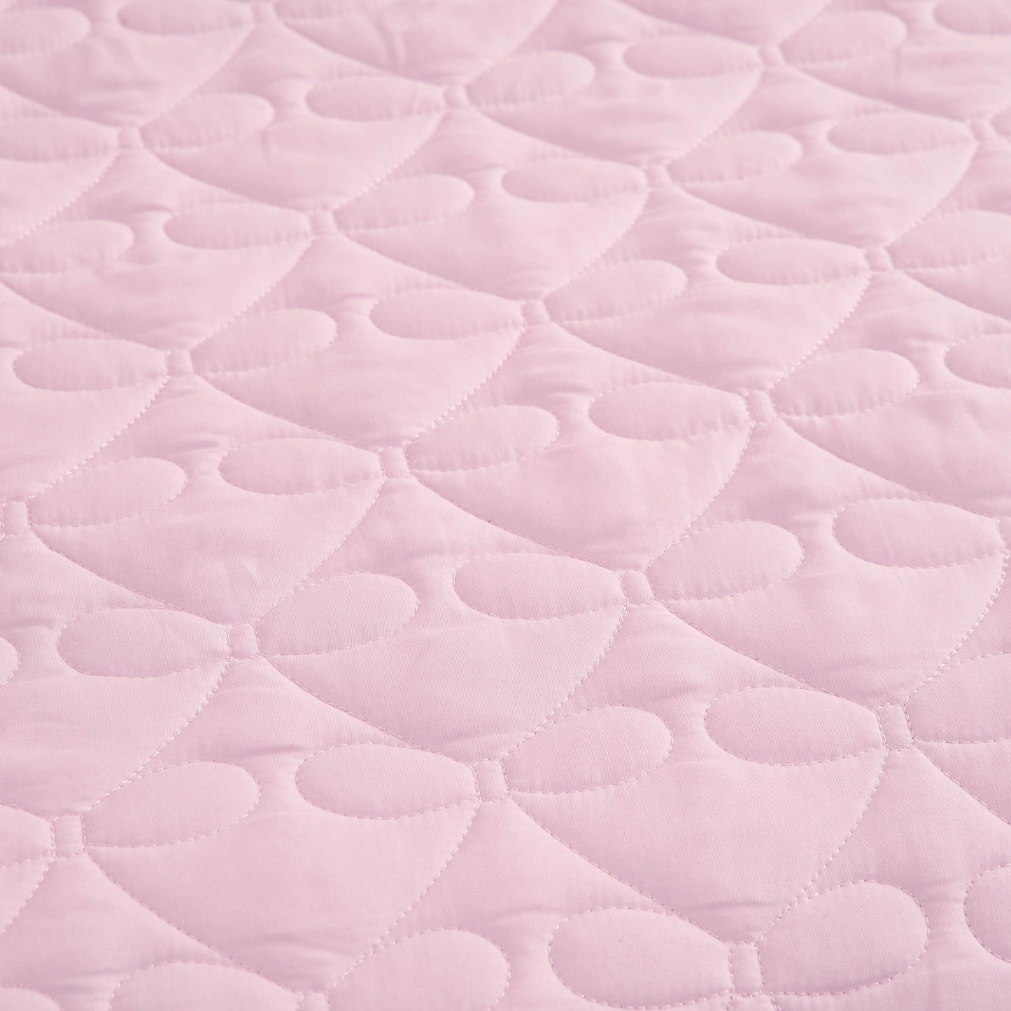 Light pink quilted fabric with a repeating pattern of stitched hearts and rounded shapes, reminiscent of the Luxe Bow Reversible Quilt Set, creates a soft, textured surface perfect for cozy microfiber comforters or bow print bedding ensembles.