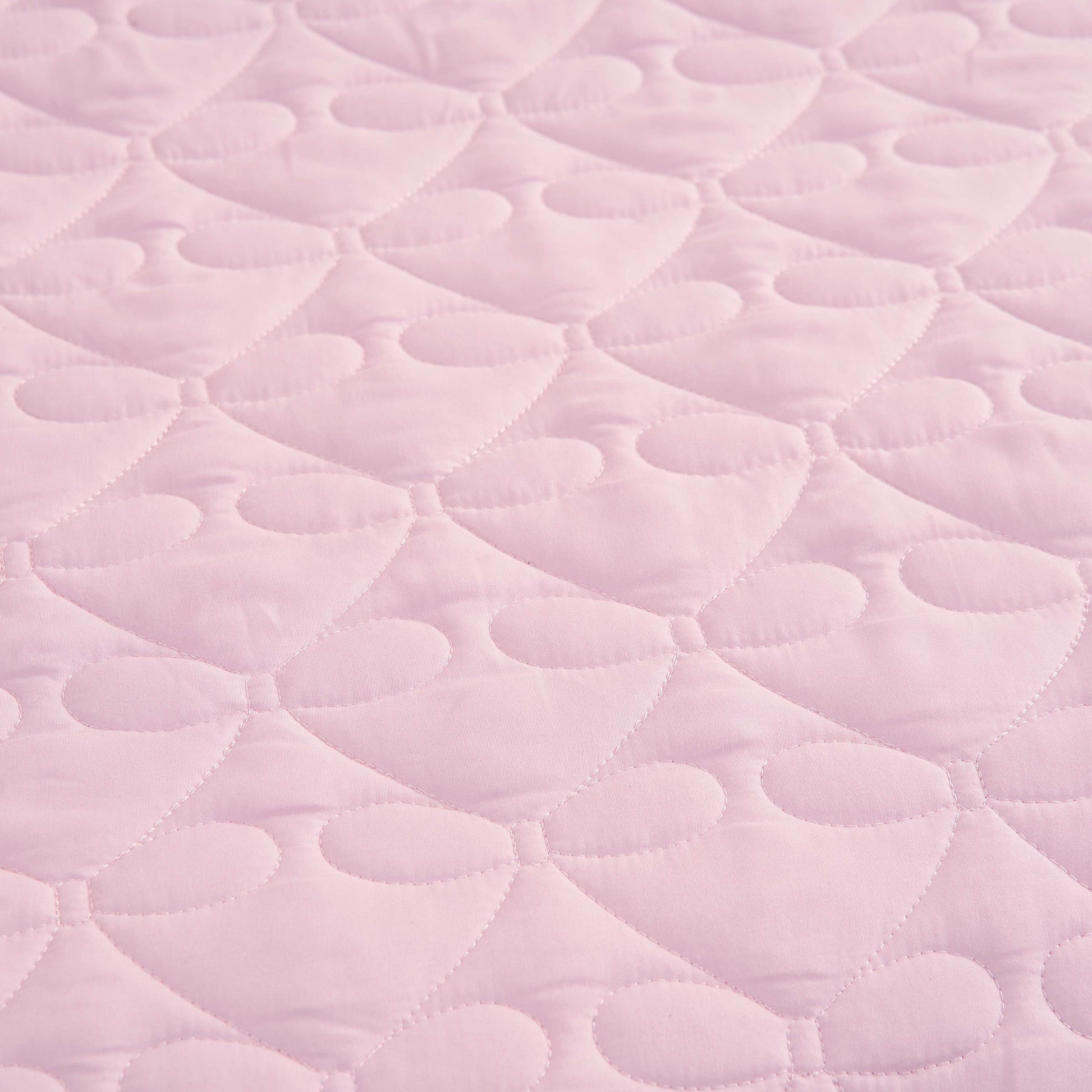 Light pink quilted fabric with a repeating pattern of stitched hearts and rounded shapes, reminiscent of the Luxe Bow Reversible Quilt Set, creates a soft, textured surface perfect for cozy microfiber comforters or bow print bedding ensembles.