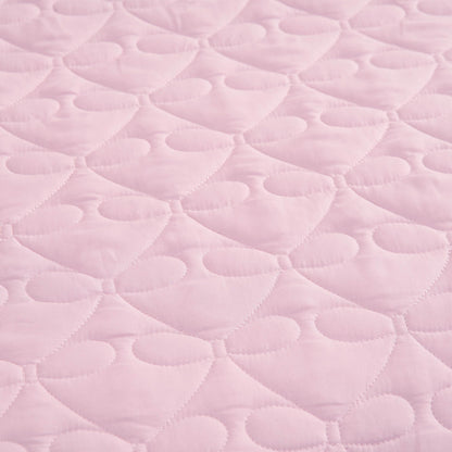 Light pink quilted fabric with a repeating pattern of stitched hearts and rounded shapes, reminiscent of the Luxe Bow Reversible Quilt Set, creates a soft, textured surface perfect for cozy microfiber comforters or bow print bedding ensembles.