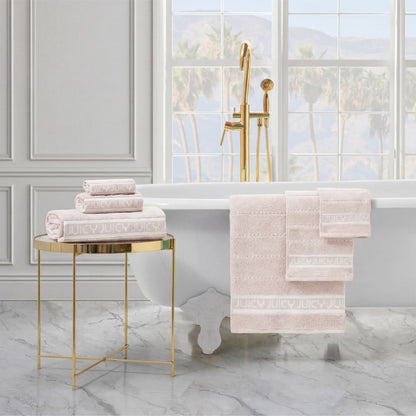 Luxurious bathroom with a white clawfoot tub, gold fixtures, and a side table holding folded JUICY ultra-soft towels. The Plush Stripe Bath Towel Set and more towels hang on the tub. A large window reveals a scenic outdoor view.