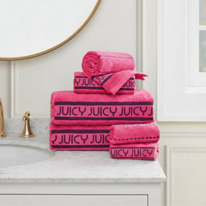 A stack of Plush Stripe Bath Towel Set towels sits on a marble counter near a gold faucet, under a round mirror and beside a window.