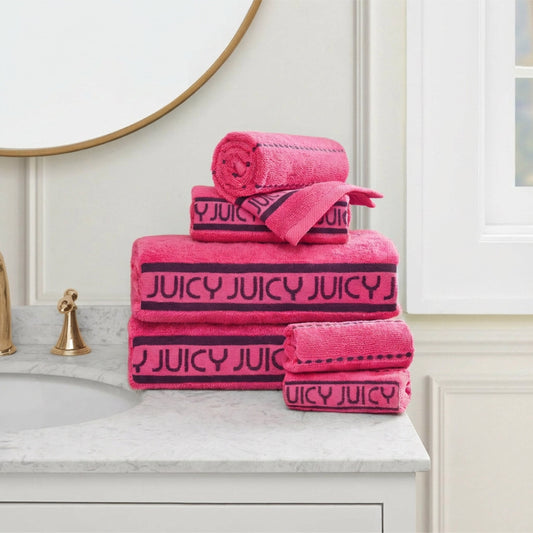 A stack of Plush Stripe Bath Towel Set towels sits on a marble counter near a gold faucet, under a round mirror and beside a window.