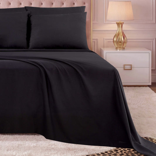 A neatly made bed with the Microfiber Sheet Set With Extra Pillowcases, featuring sleek black sheets and pillows, sits next to a white nightstand with a gold lamp. The room showcases a tufted headboard, paneled walls, and a white rug with a leopard print edge.