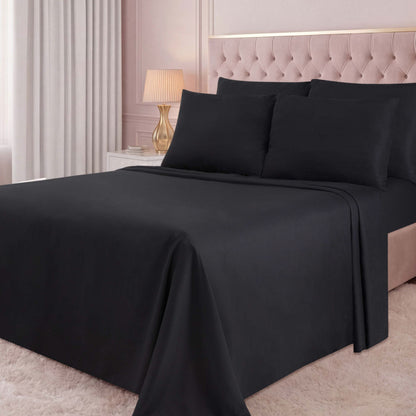 A neatly made bed with black sheets and pillowcases in a softly lit bedroom featuring light pink walls, a beige tufted headboard, a gold lamp, white curtains, and a white plush rug. The luxurious look is elevated by the addition of the Microfiber Sheet Set With Extra Pillowcases, bringing both comfort and style to the space.