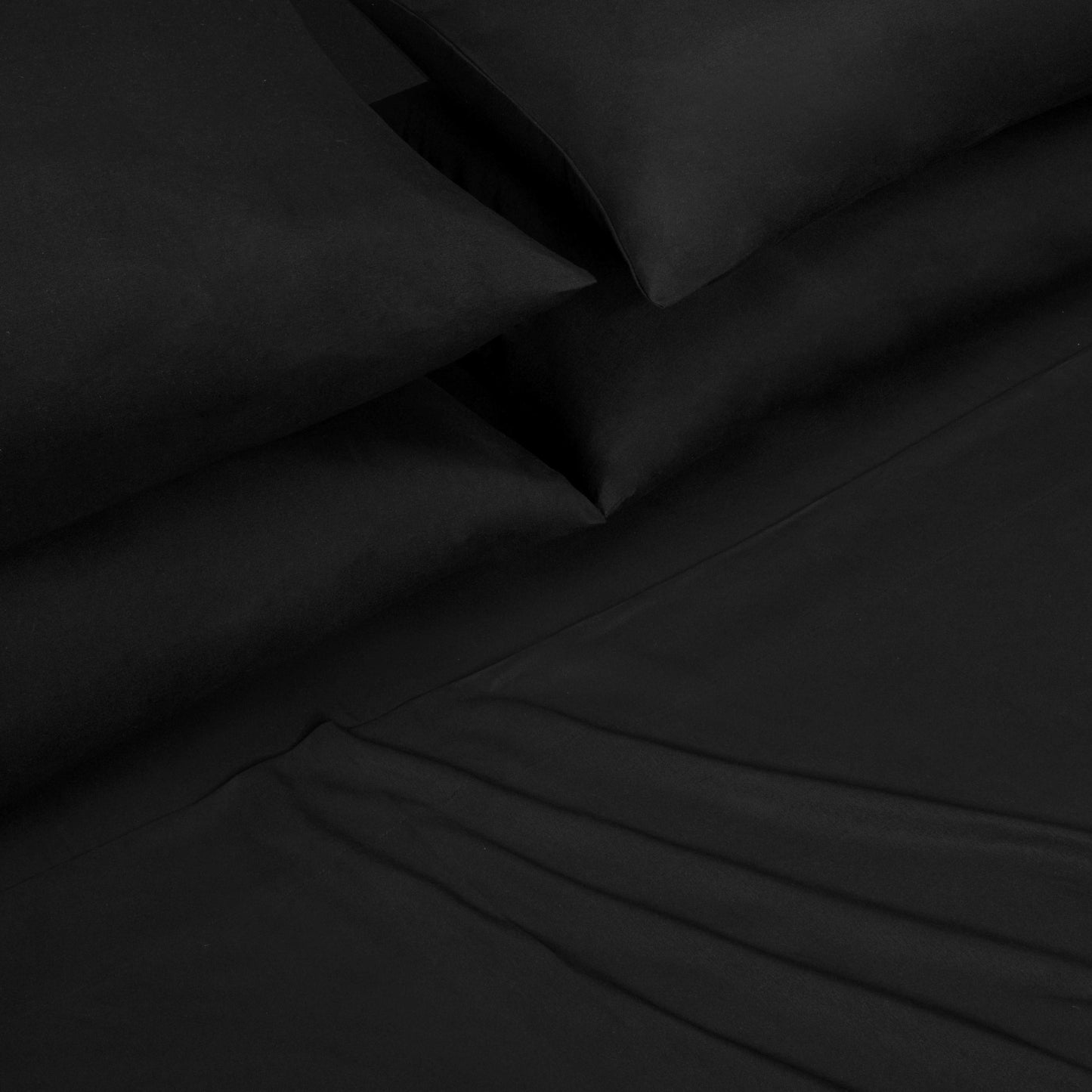 A close-up of a neatly made bed featuring the Microfiber Sheet Set With Extra Pillowcases, displaying smooth black pillowcases and a matching fitted sheet with subtle folds, all part of a luxury bedding collection.