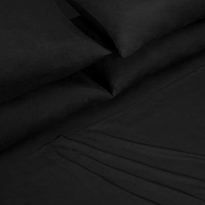 A close-up of a neatly made bed featuring the Microfiber Sheet Set With Extra Pillowcases, displaying smooth black pillowcases and a matching fitted sheet with subtle folds, all part of a luxury bedding collection.