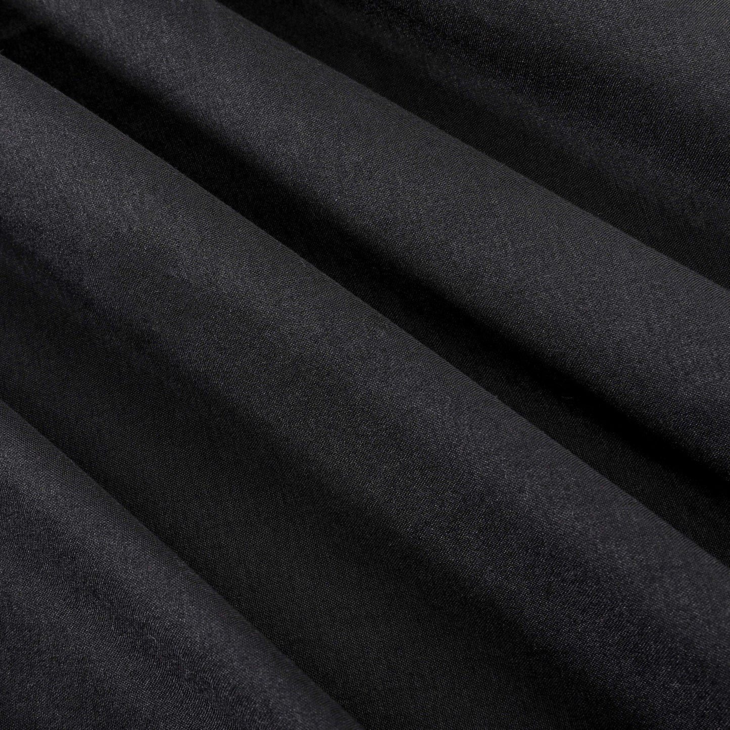 Close-up of smooth, black fabric with diagonal folds creating soft shadows and highlights across the surface, evoking the elegance of a luxury bedding collection such as the Microfiber Sheet Set With Extra Pillowcases.