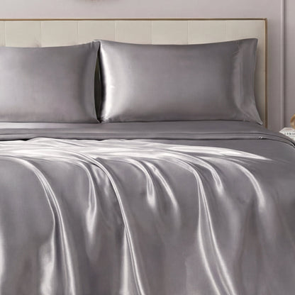 A neatly made bed showcases the Solid Satin Sheet Set with ultra-soft sheets and pillowcases, paired with a light-colored upholstered headboard for a luxurious, elegant look.