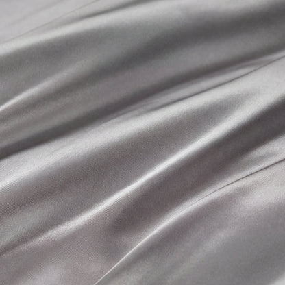 Smooth, shiny silver-gray fabric with gentle folds and soft reflections highlights the silky texture of the Solid Satin Sheet Set—perfect for adding a touch of ultra-soft luxury to your bedroom.