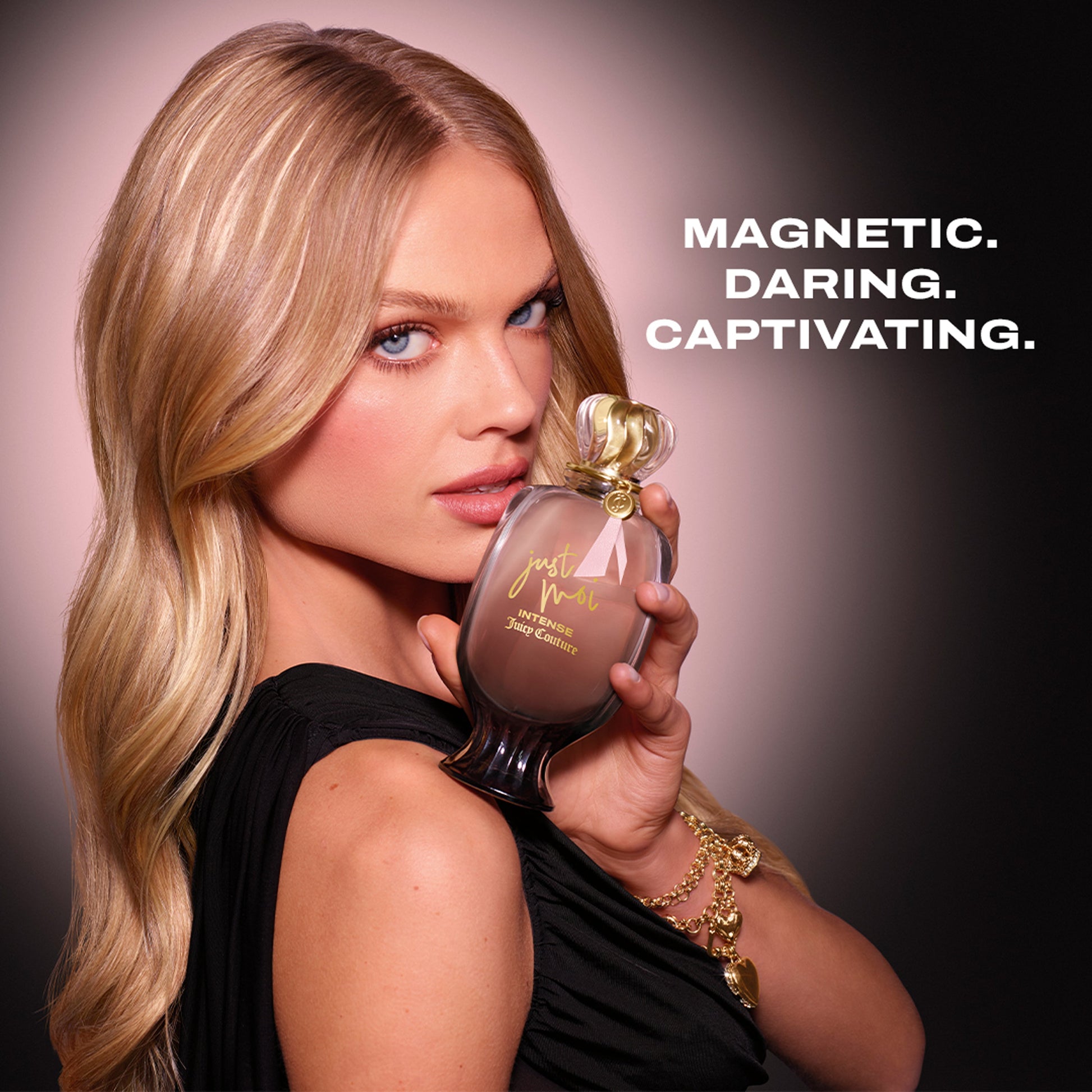 A woman with long blonde hair holds a Just Moi Intense Eau de Parfum Spray Pen, 0.33 oz, near her face. She wears a black dress and gold bracelet. Bold text on the right reads: “MAGNETIC. DARING. CAPTIVATING.”.